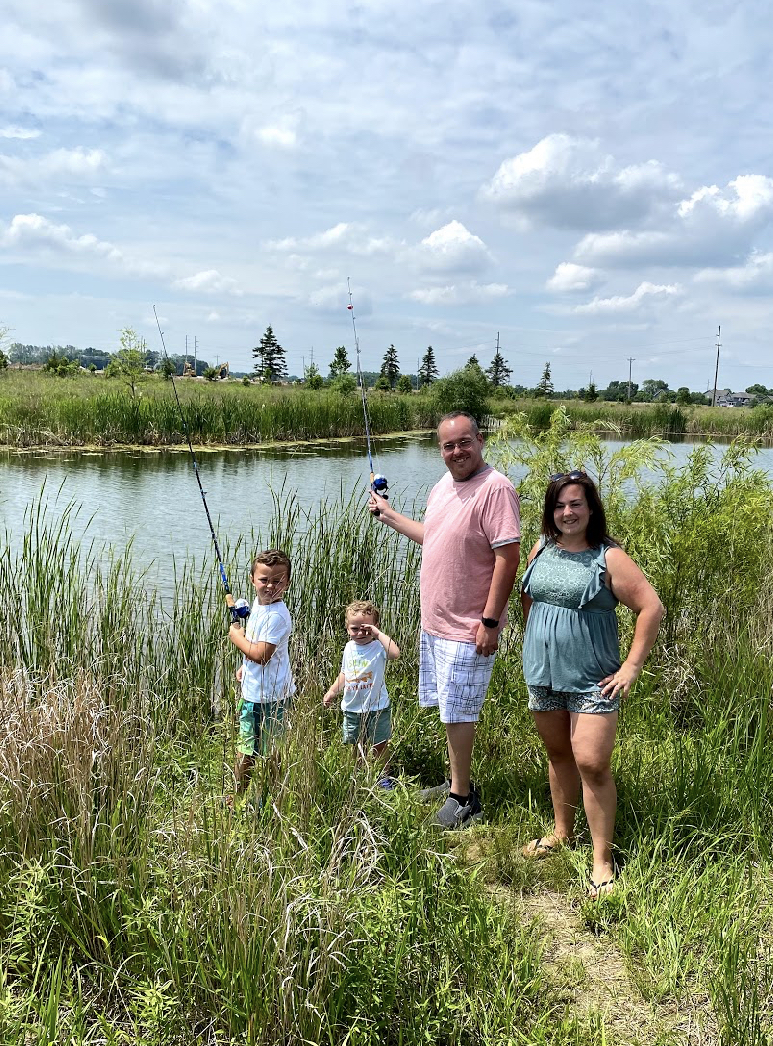 a family posing and smiling in front of a pond