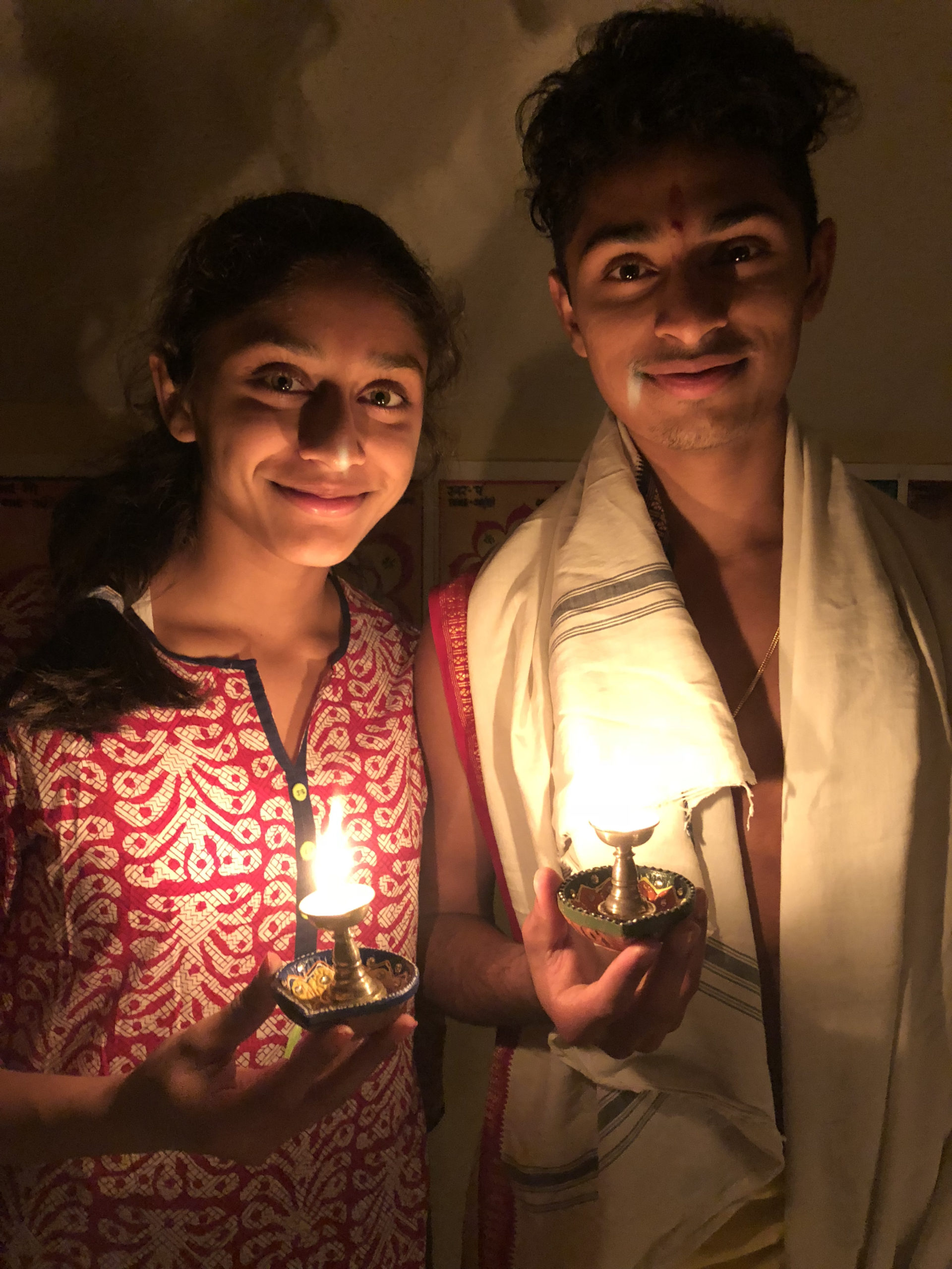 a brother and sister holding diyas
