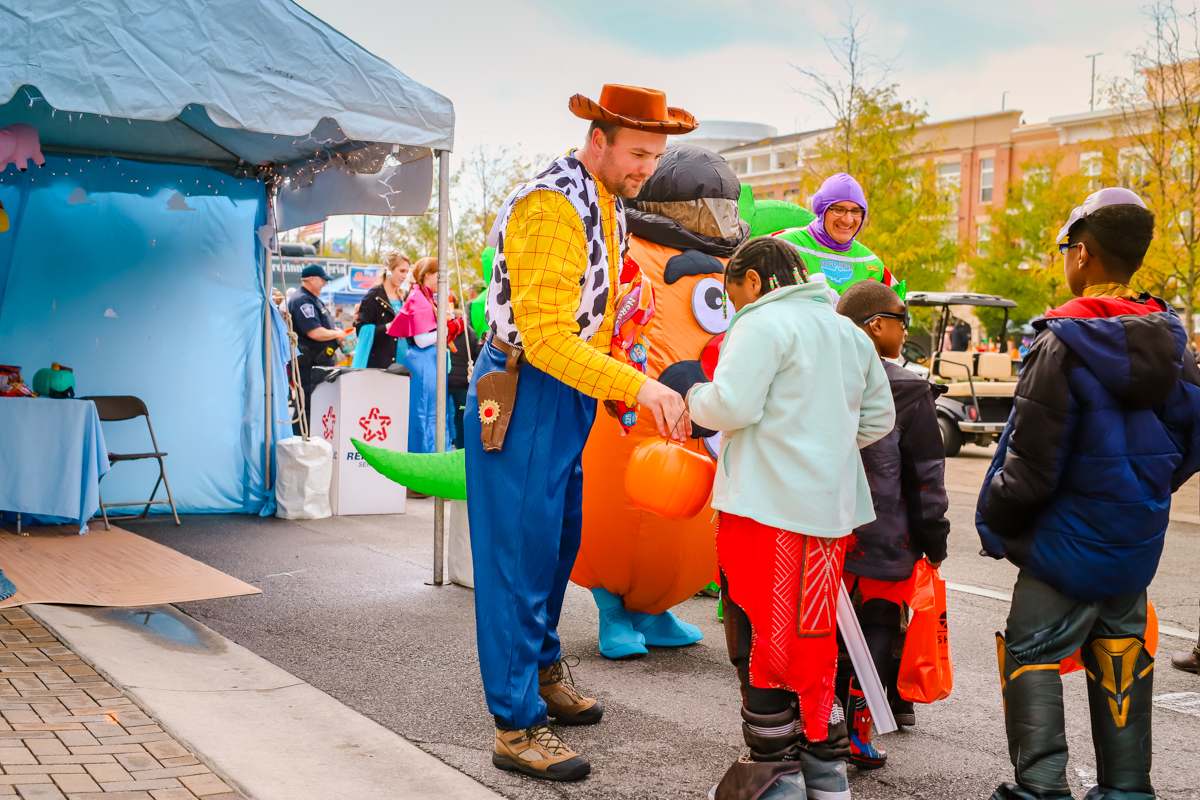 a person dressed up as woody from toy story handing candy to kids at a trick or treat event