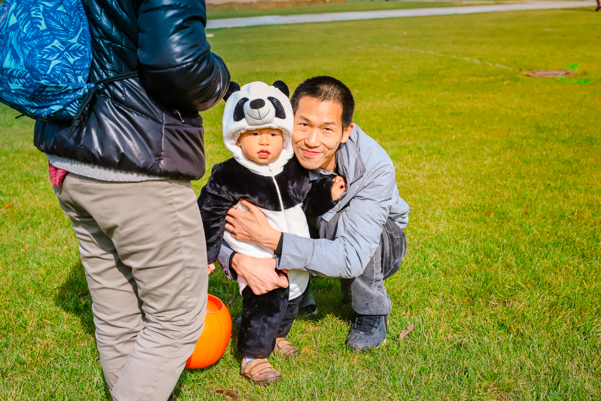 a dad hugging his child in their panda halloween costume