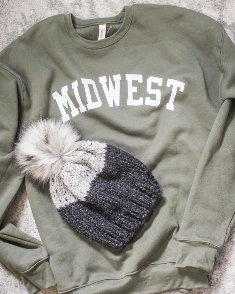 a green crew neck that says midwest and a beanie on top of it