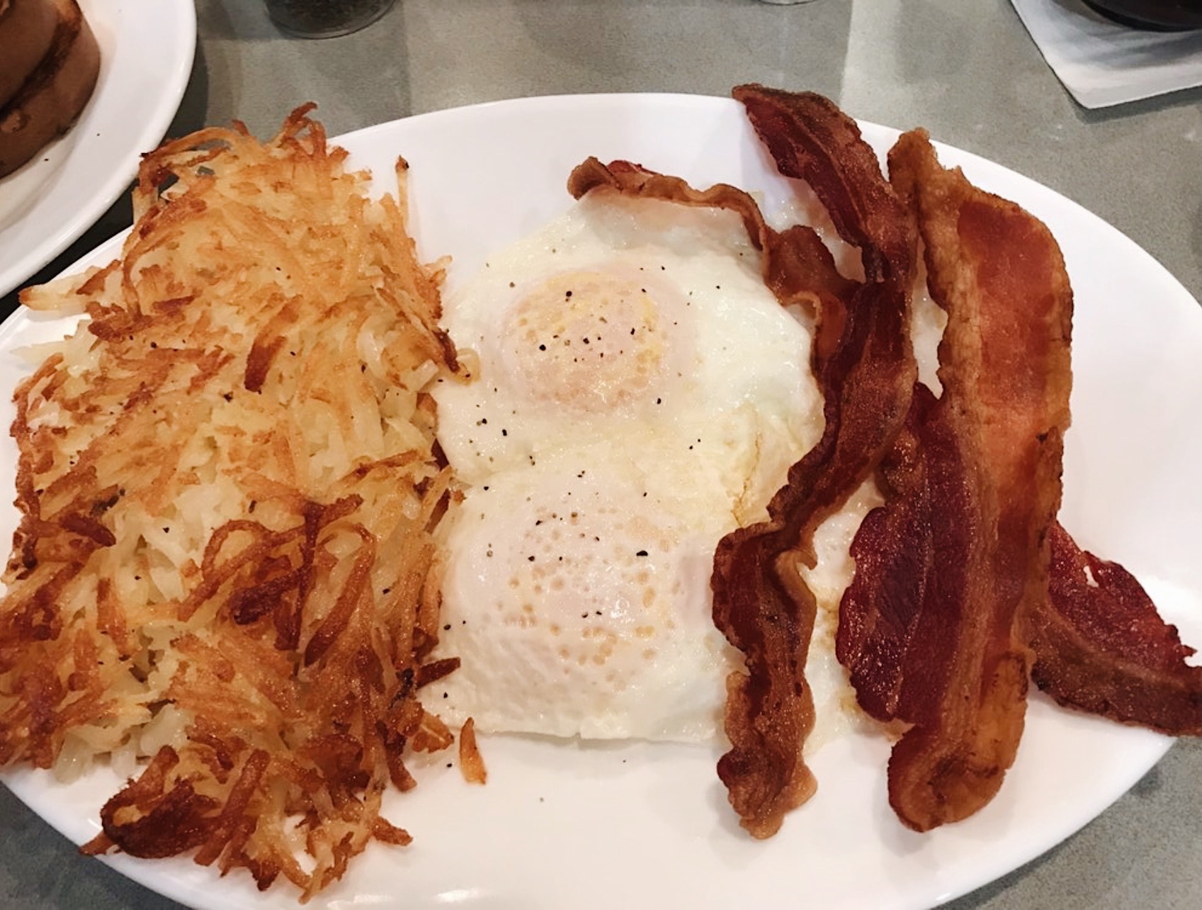 a plate with hashbrowns, eggs and bacon