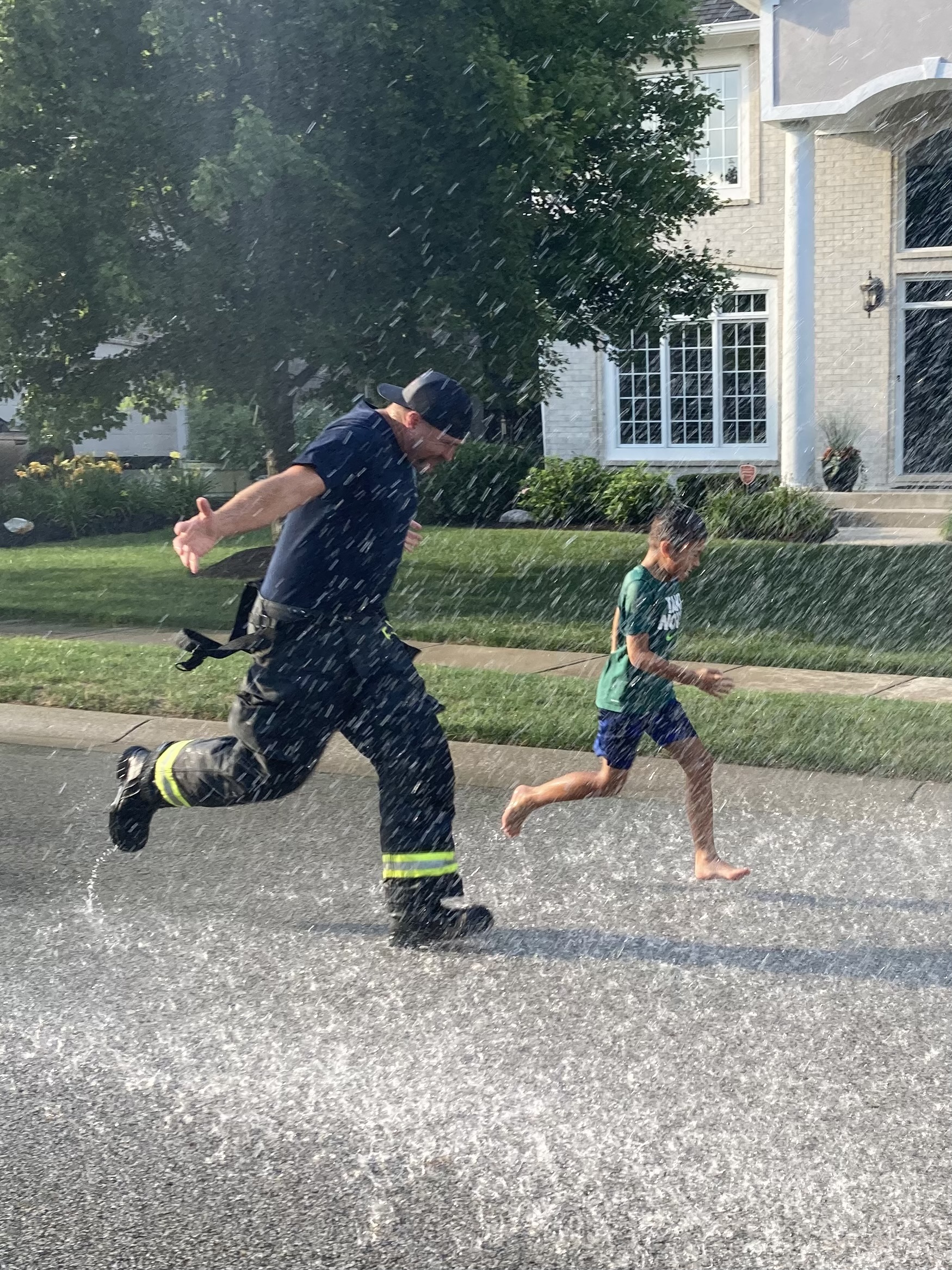 fireman and child running through sprayed water