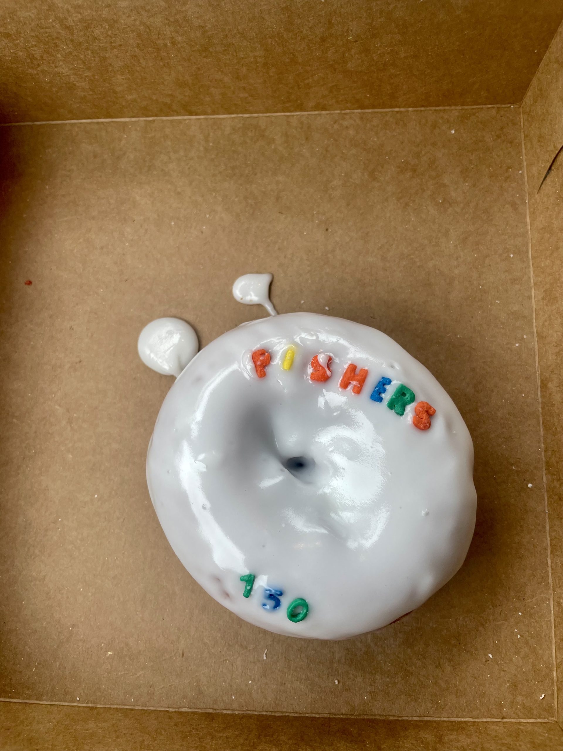 donut with white frosting and sprinkles spelling Fishers 150
