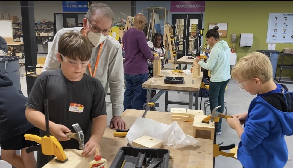 Reece helping students use wood tools