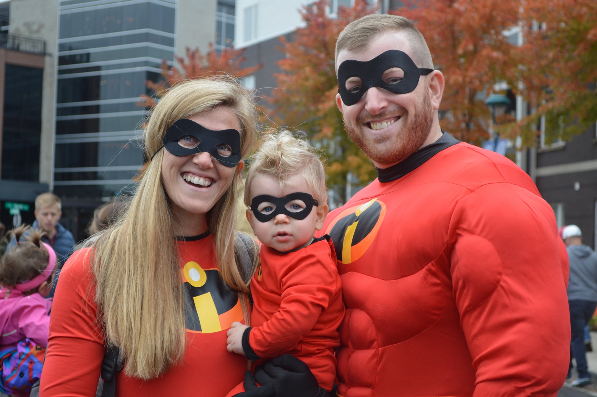 Woman, baby and man in red costumes smiling