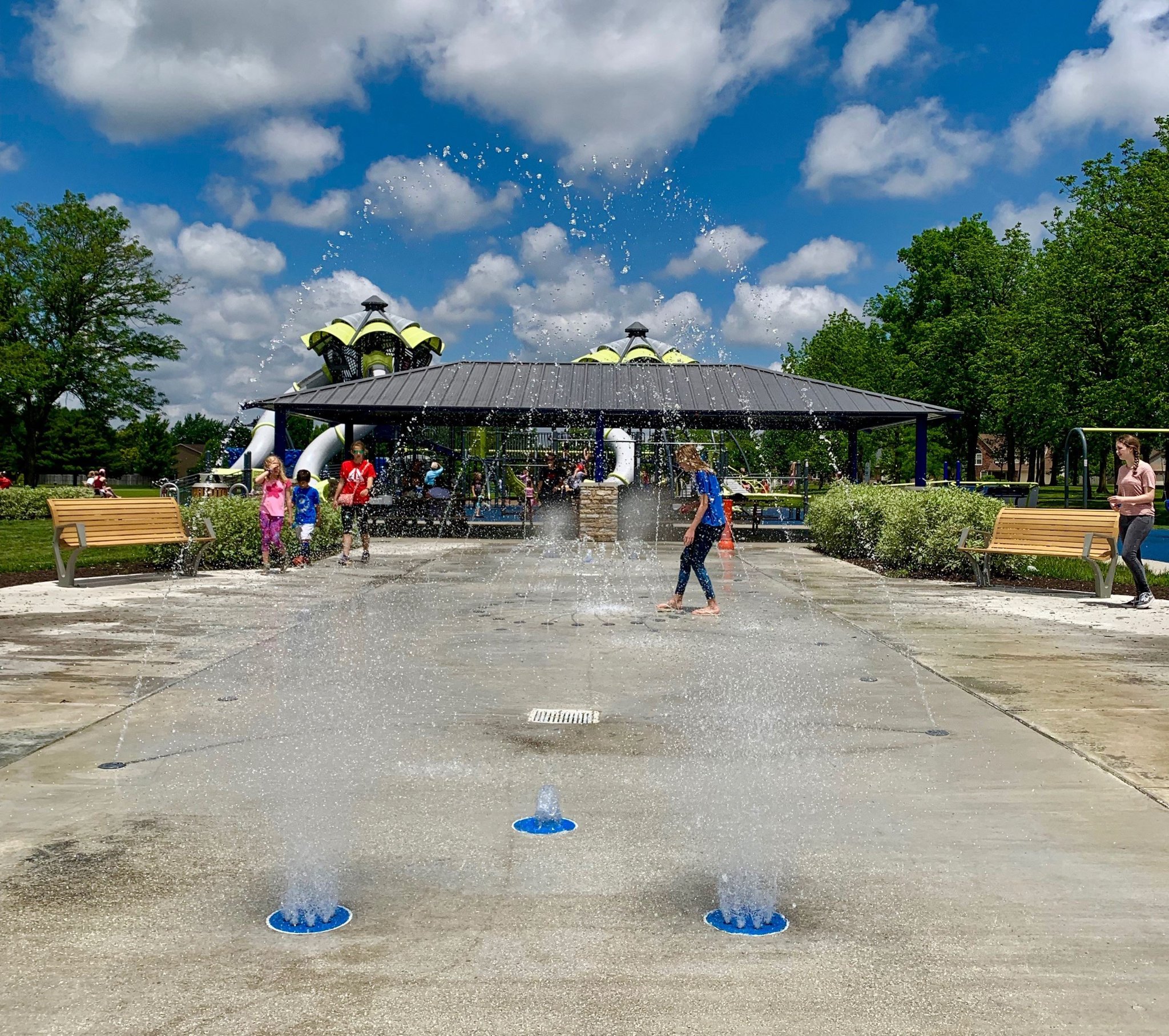 people playing in the water at the splash pad